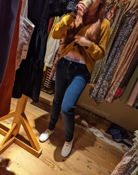 A girl in tight jeans lifts her shirt to unveil her bare belly and cute diaper.