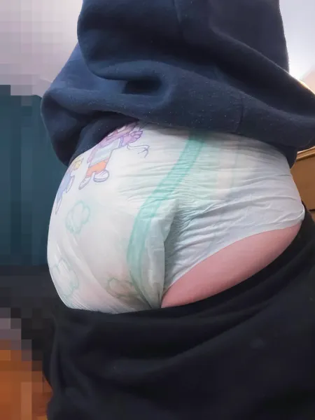A girl showing off her backside with her pants pulled down just enough to reveal a glimpse of her diaper.