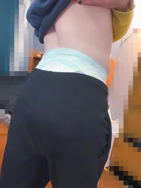 A girl lifting her top to show off her diaper waistband.