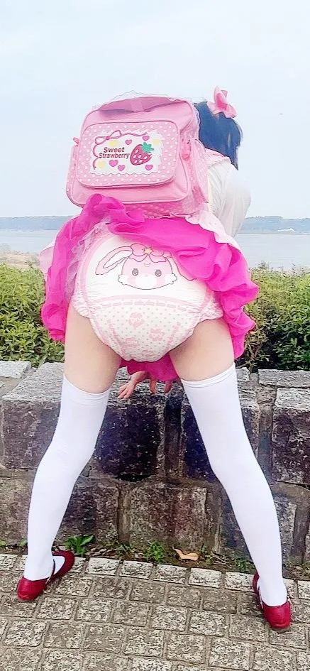 The girl is dressed in an infantile style and flaunting her rabbit ABDL diaper outdoors. She is wearing white stockings.