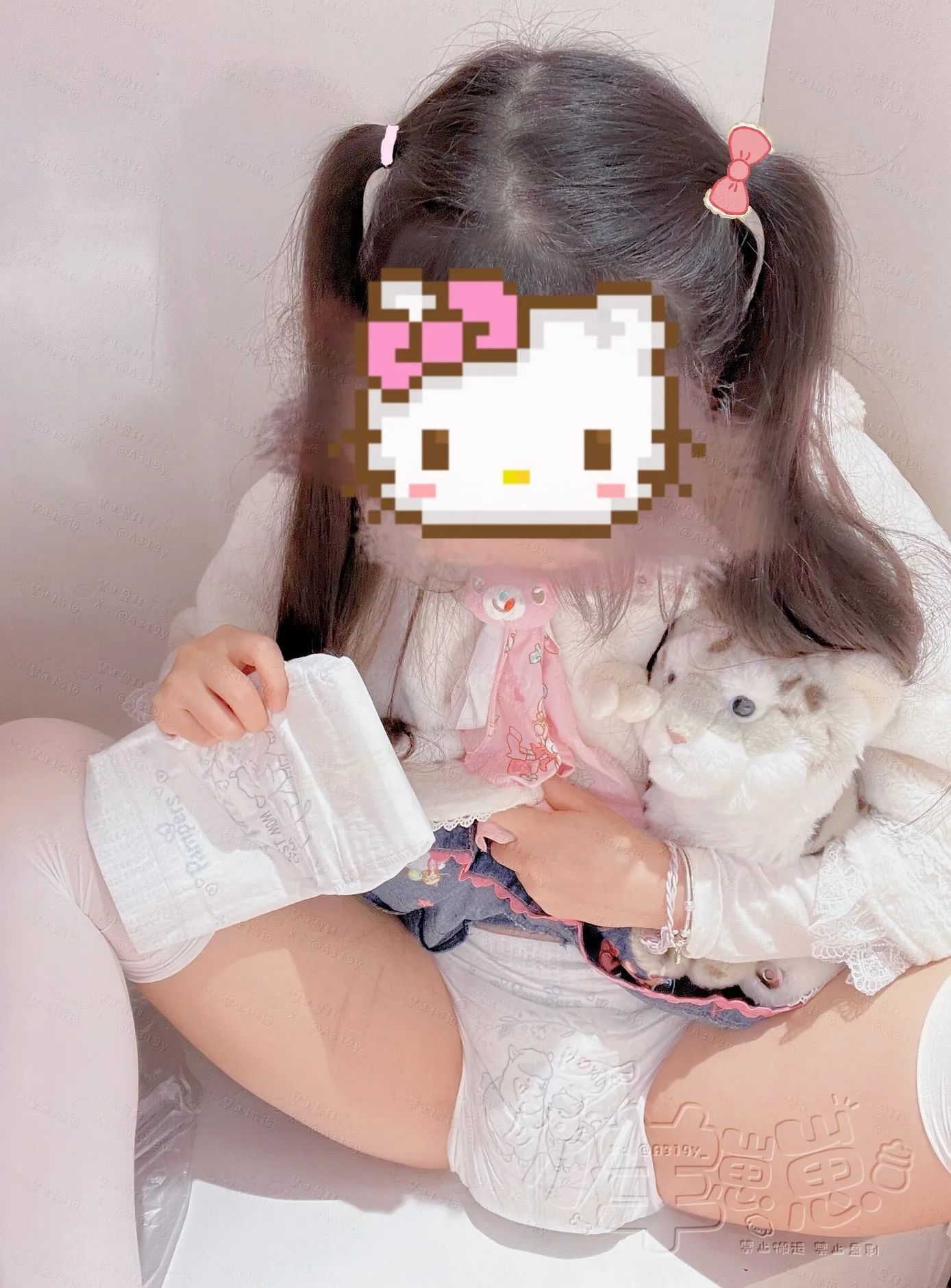The girl is sitting with her legs spread, wearing a wet diaper.