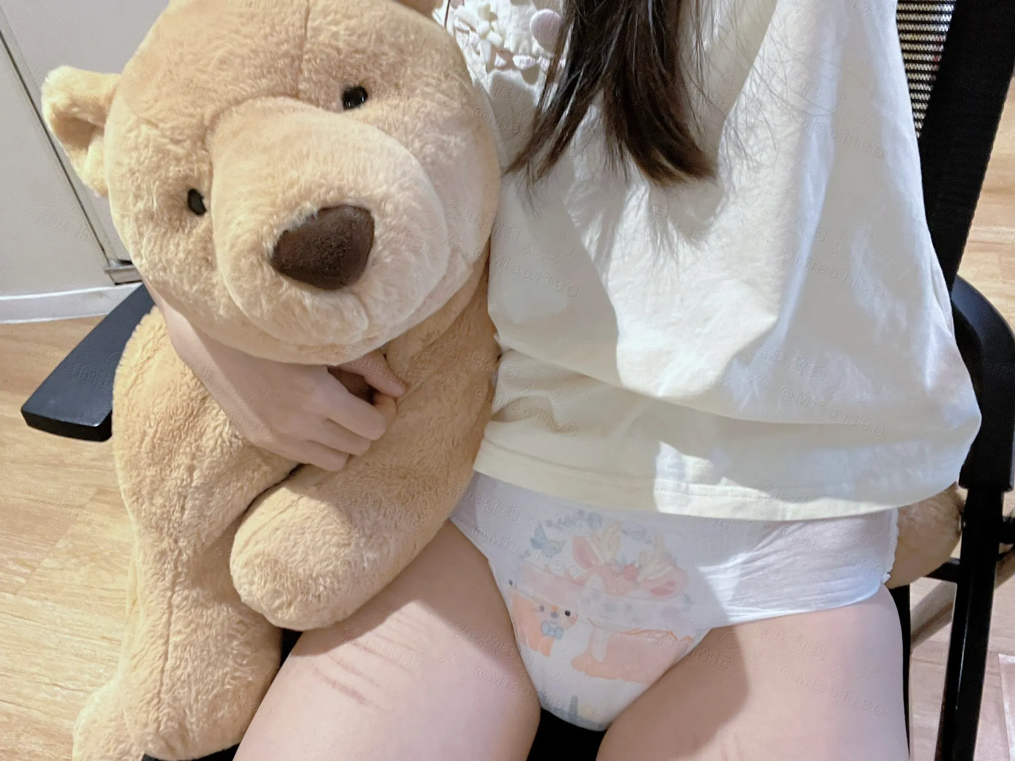 An ABDL girl hugging a teddy bear and wearing paper diapers