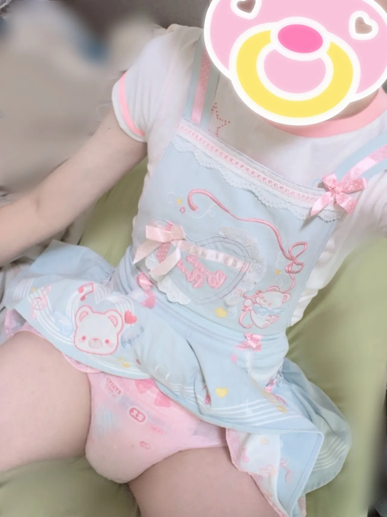 An ABDL girl sits on the bed, lifts up her skirt, and shows her diaper.