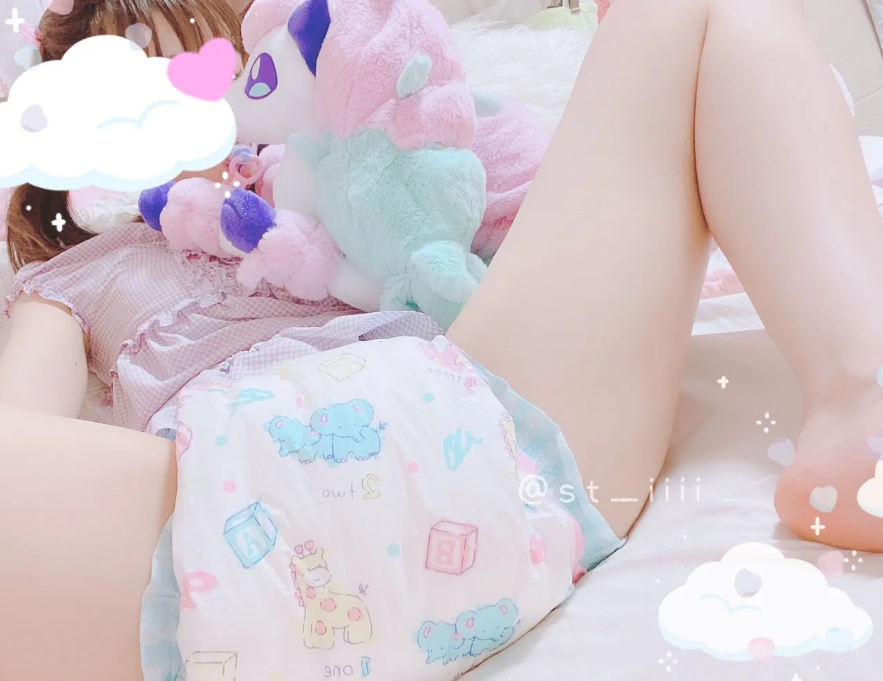 An ABDL girl is lying on the bed wearing an ABDL diaper with her legs spread apart.