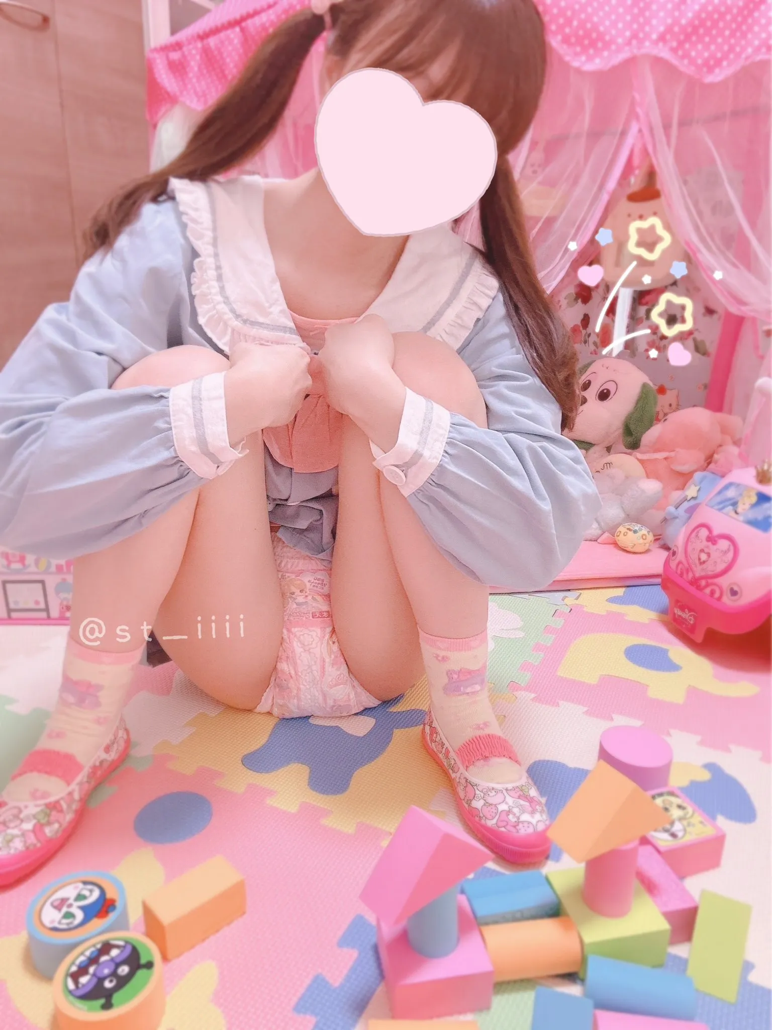An ABDL girl squats down to show off her pink diaper.