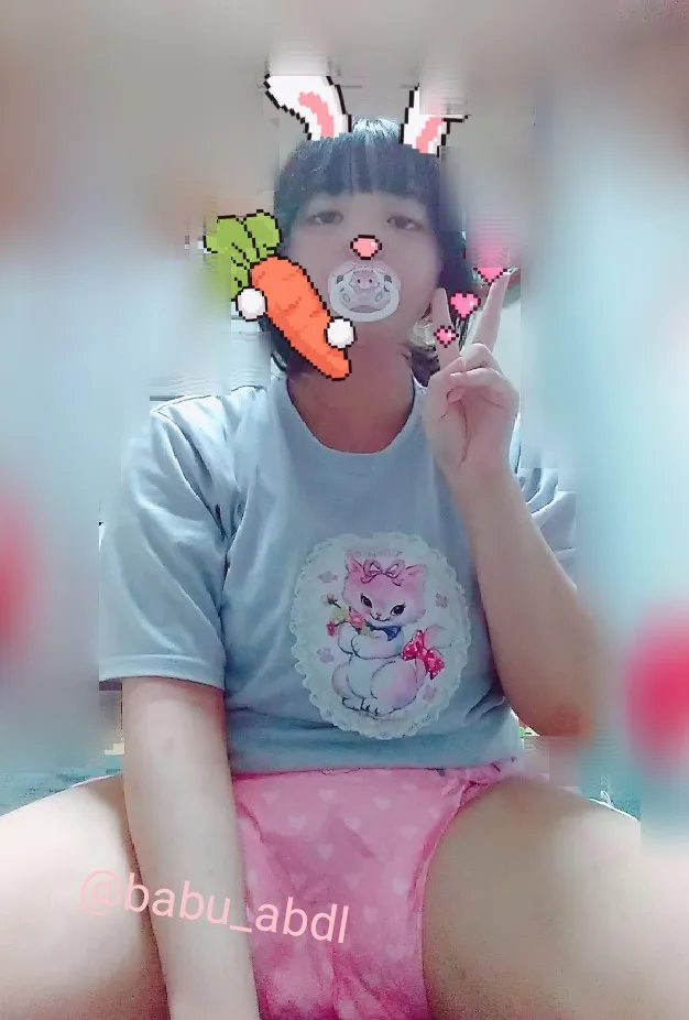 An ABDL girl is wearing a pink diaper and striking a V-sign pose.