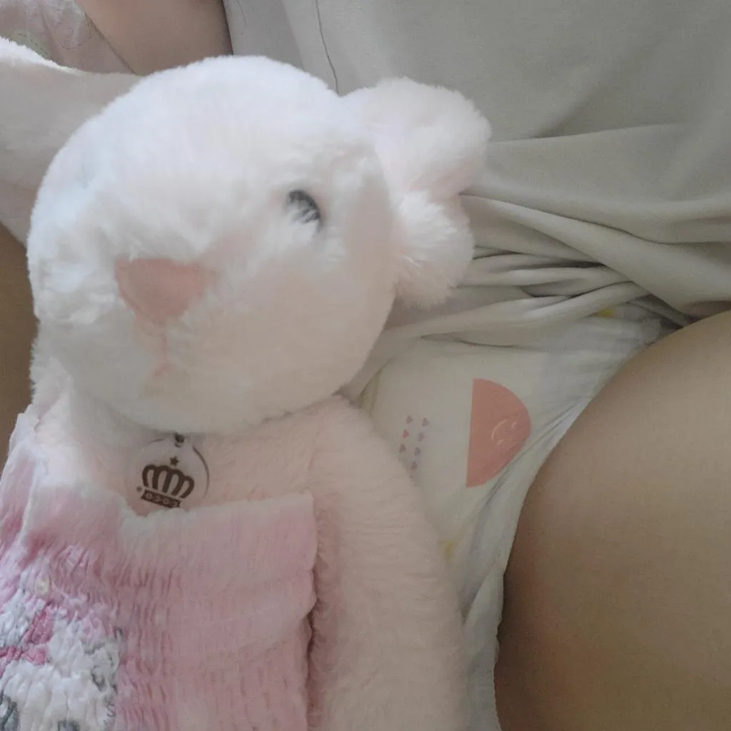 A diaper is visible behind the doll of the ABDL girl.