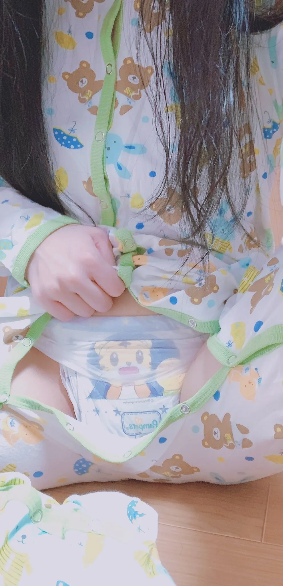 An ABDL girl unbuttoning her romper to show off her diaper