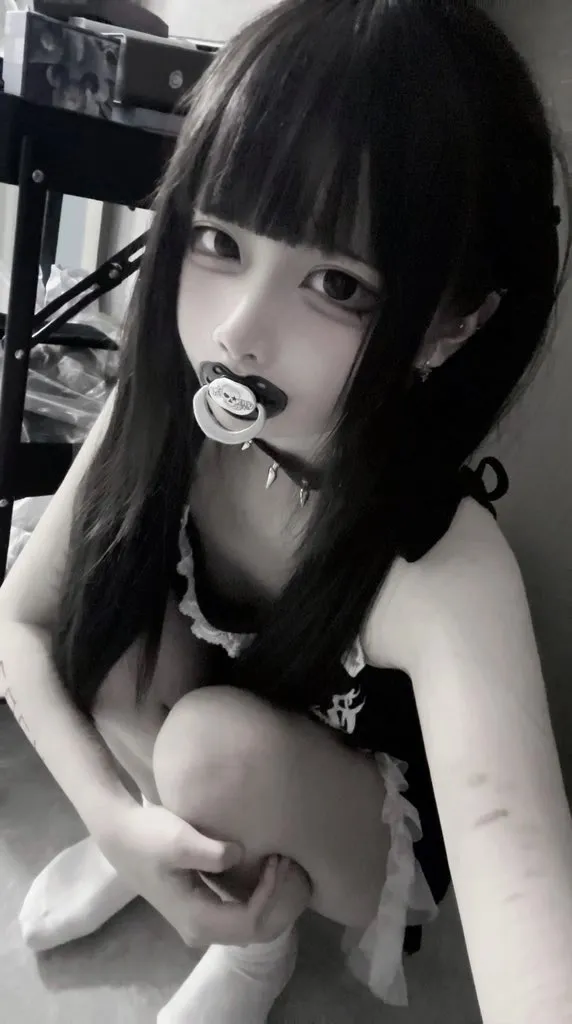 A gothic lolita ABDL girl sucking on a pacifier