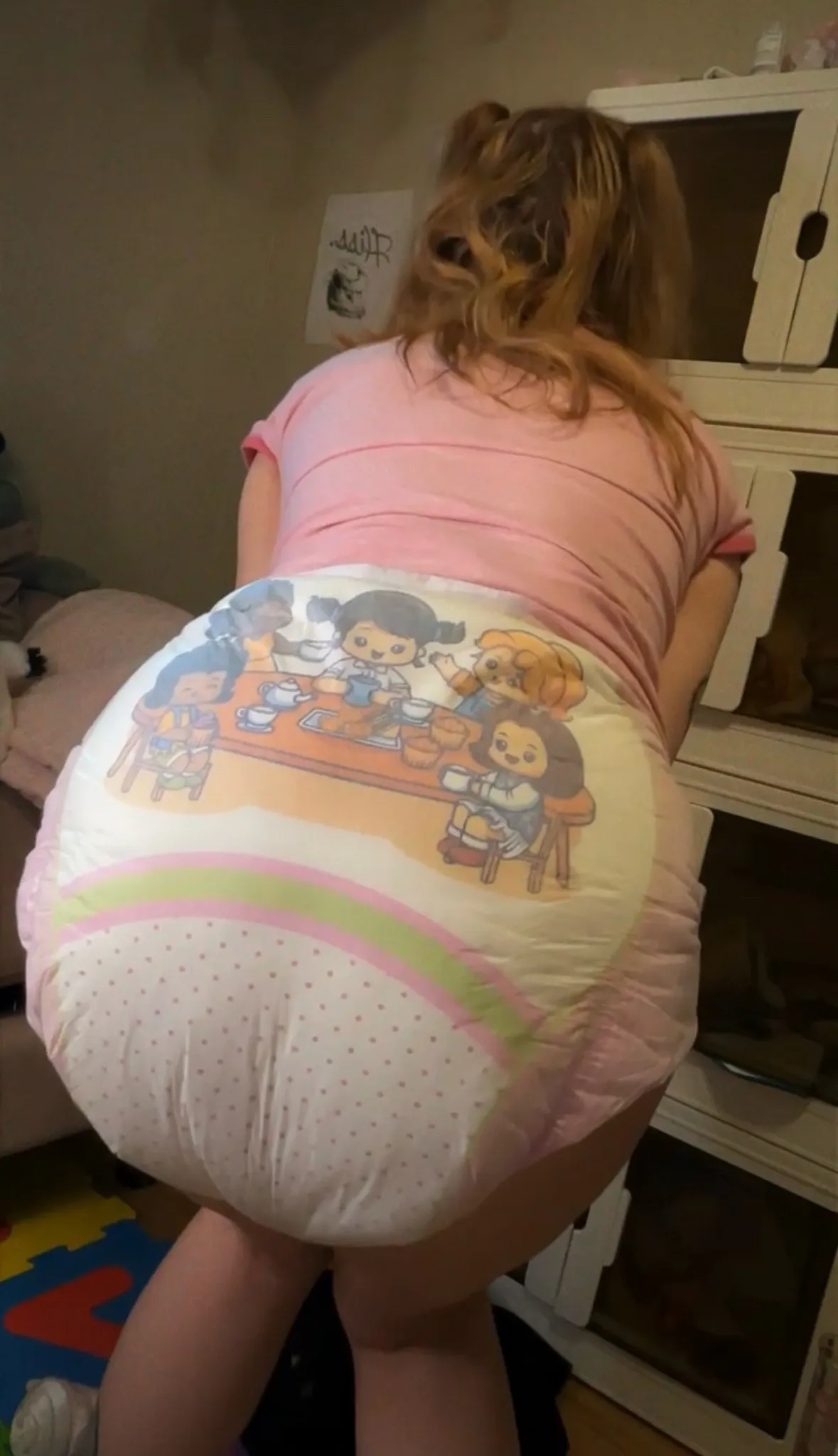 The ABDL girl is holding a diaper while striking a pose that looks like she's pooping while standing up.