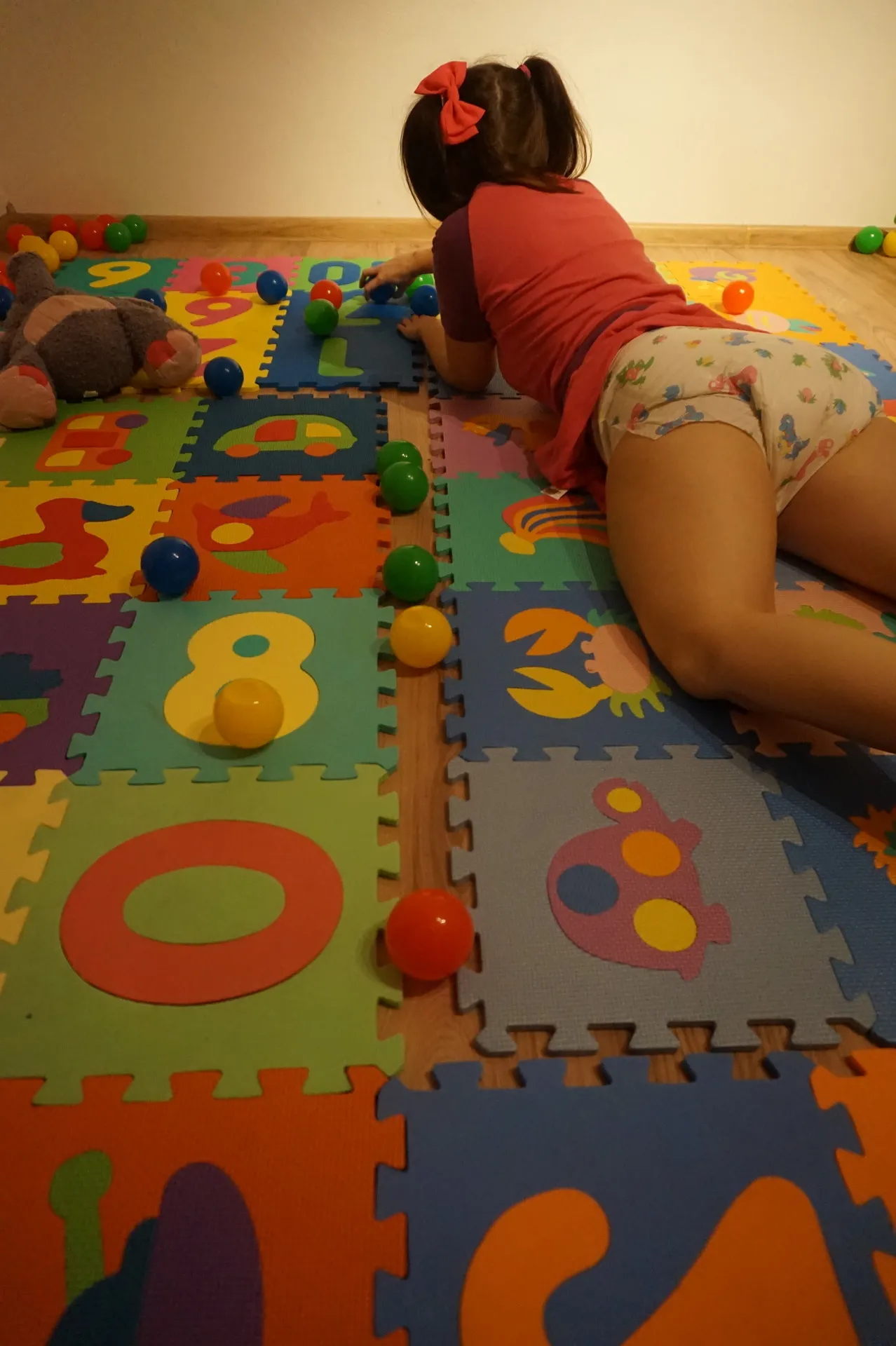 An ABDL girl is playing while wearing a diaper in the playroom.