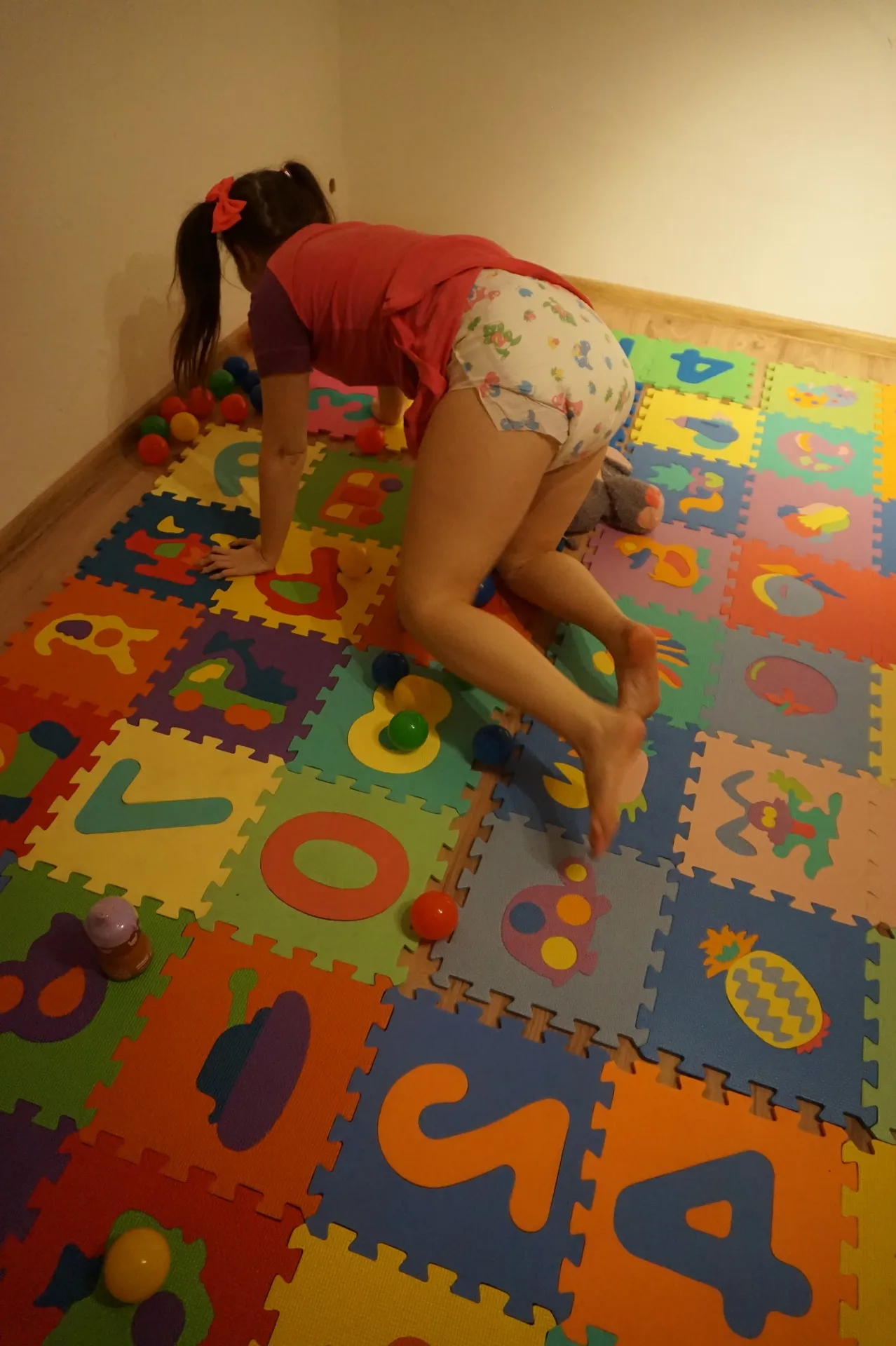 An ABDL girl is playing while wearing a diaper in the playroom.