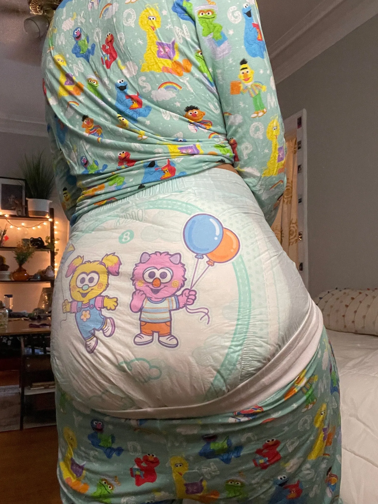 An ABDL girl pulls down the pants of her toddler pajamas and shows off her diaper.