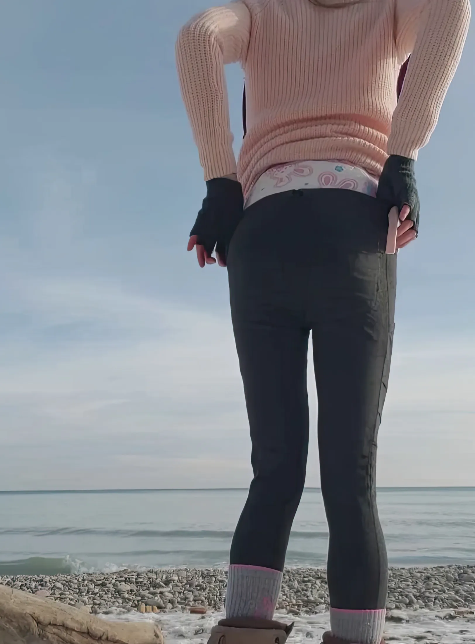 An ABDL girl slightly lifts her top outdoors to show off the top of her diaper.