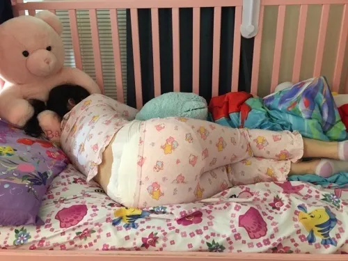 An ABDL girl lies down, proudly showing off her diaper peeking out over her pajamas.