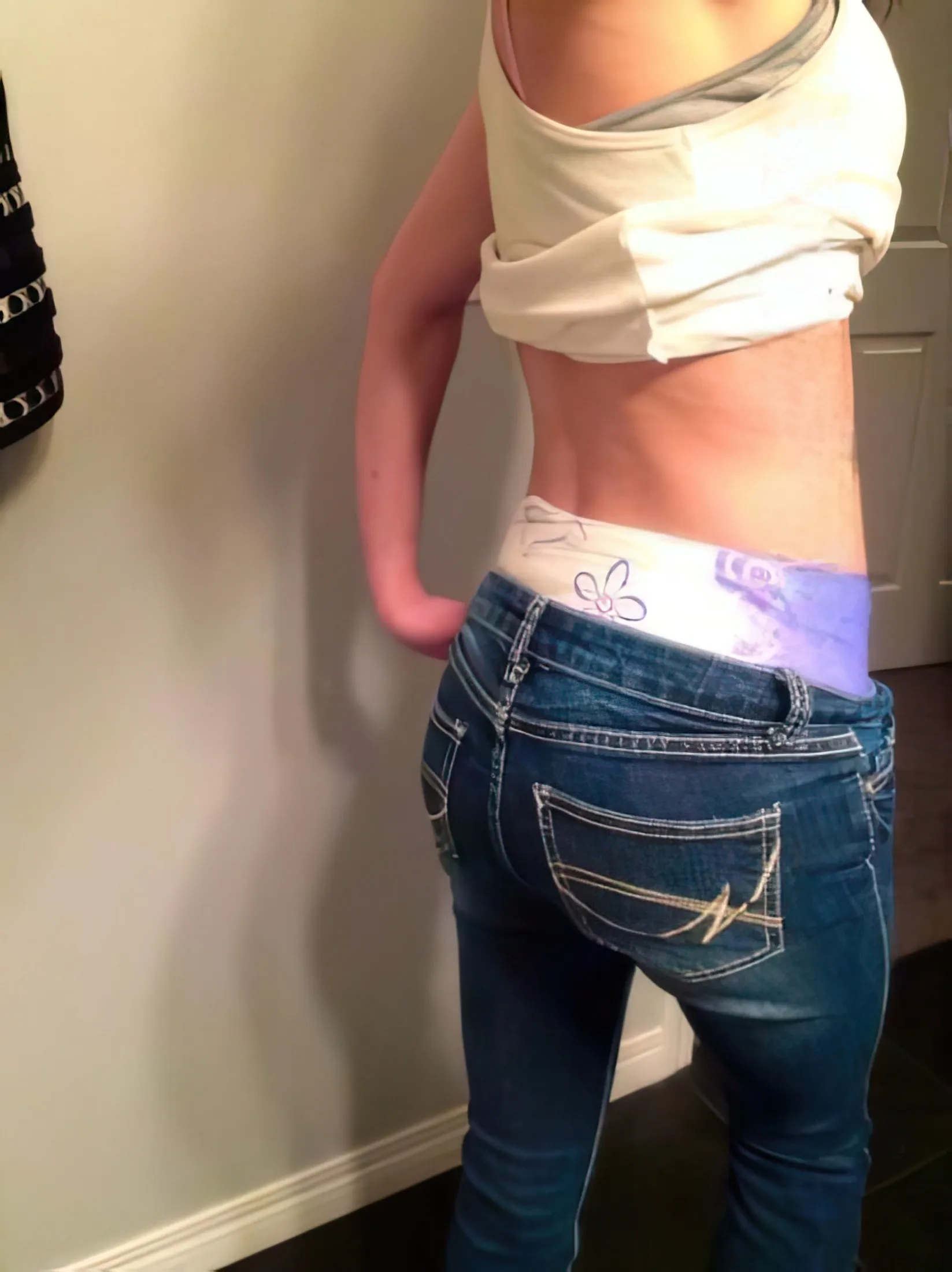 The ABDL girl shows off her diaper peeking out over her jeans.