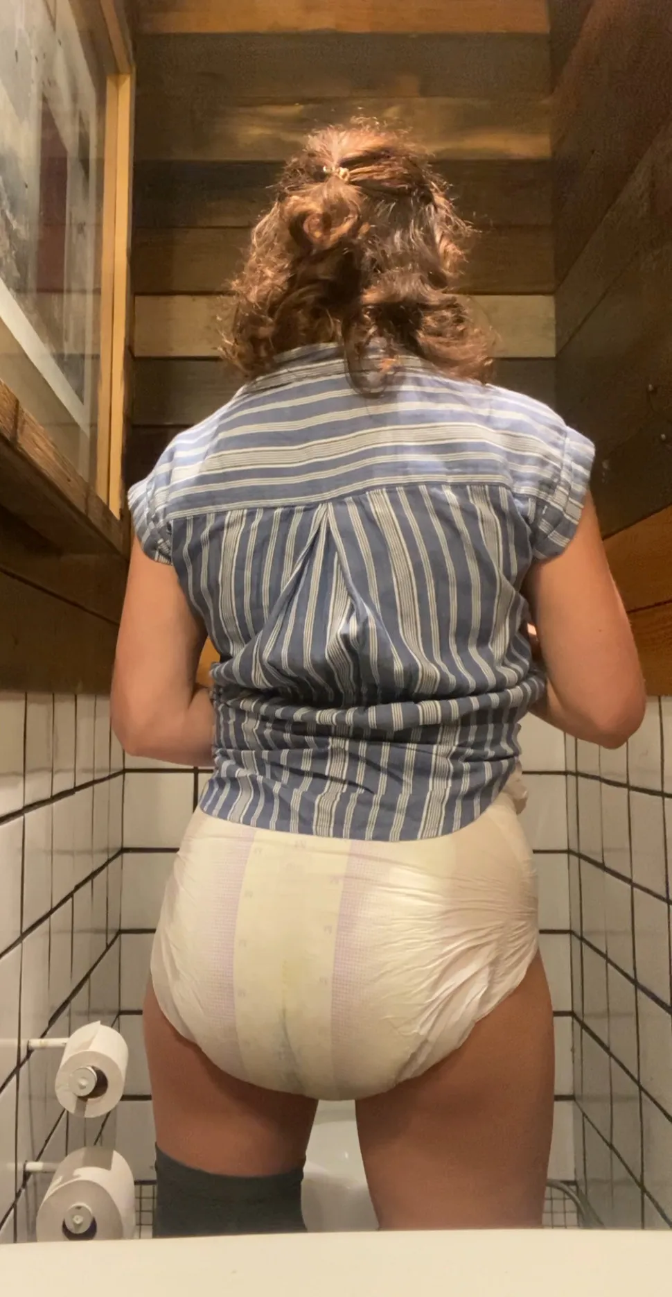 An ABDL woman shows off her rear view with a diaper filled with pee.