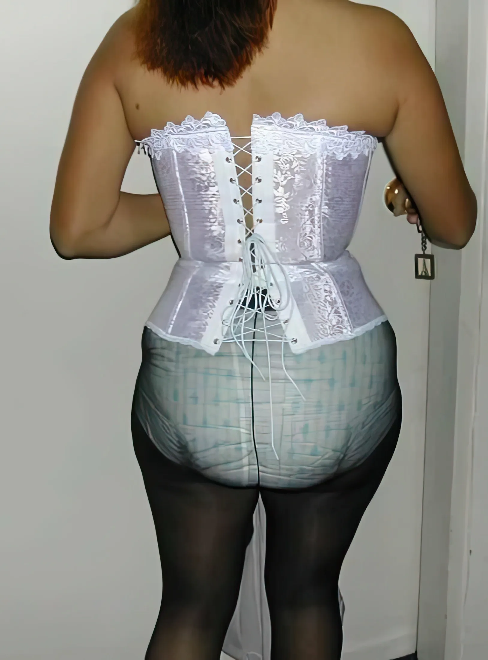 An ABDL woman wears a corset and black stockings while showing off her diaper.