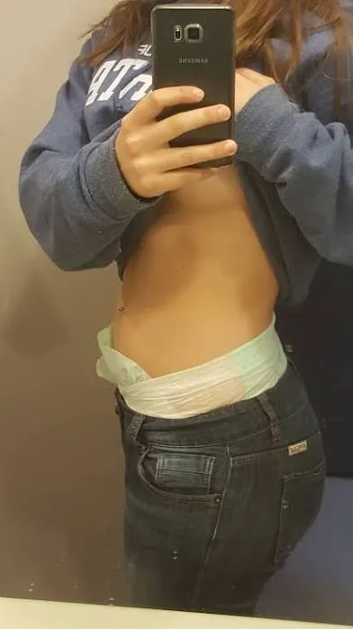 The ABDL girl lifts her top to show off her diaper waistband and underbust.