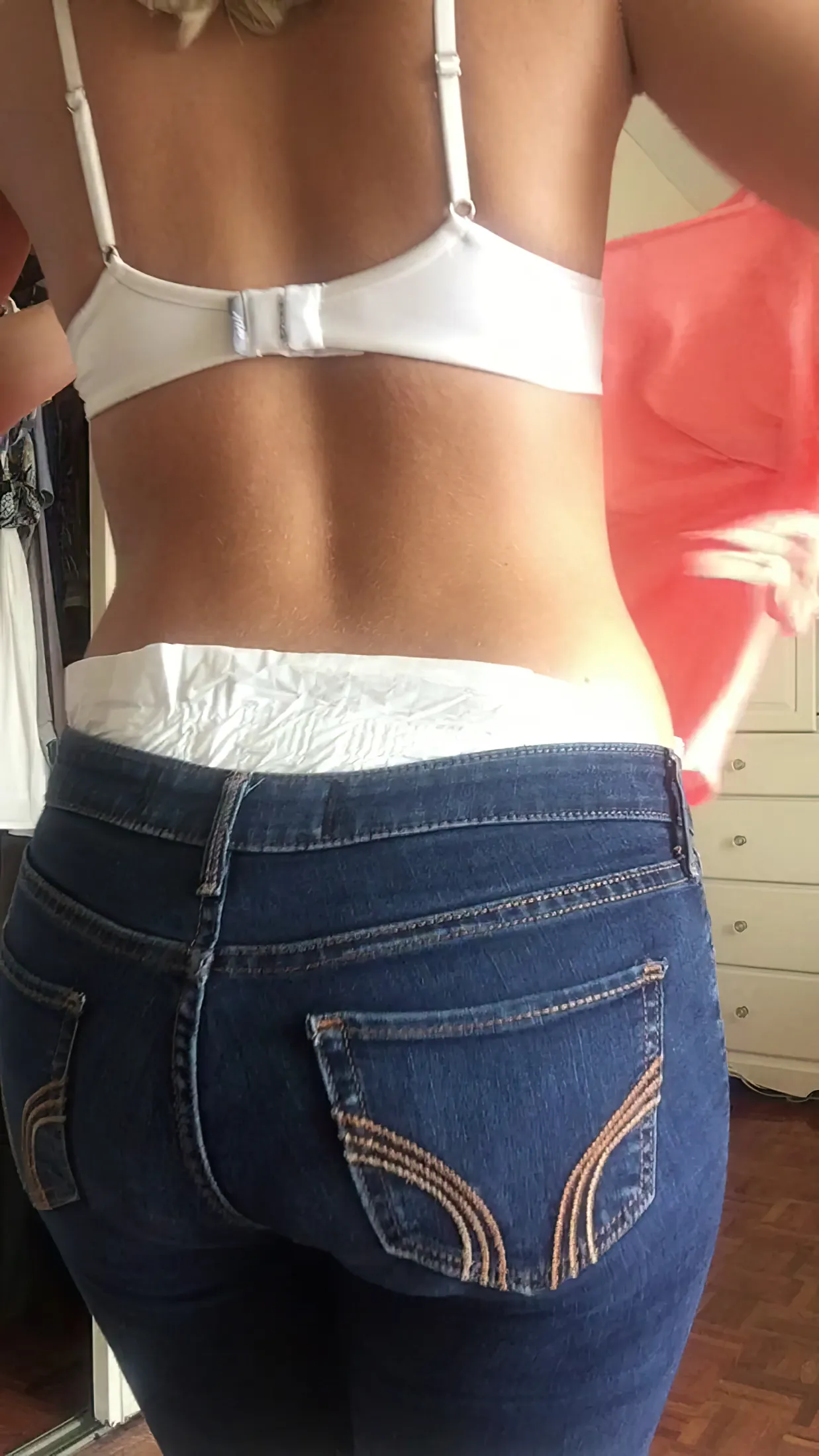The ABDL girl shows off the diaper waistband peeking out over her jeans.