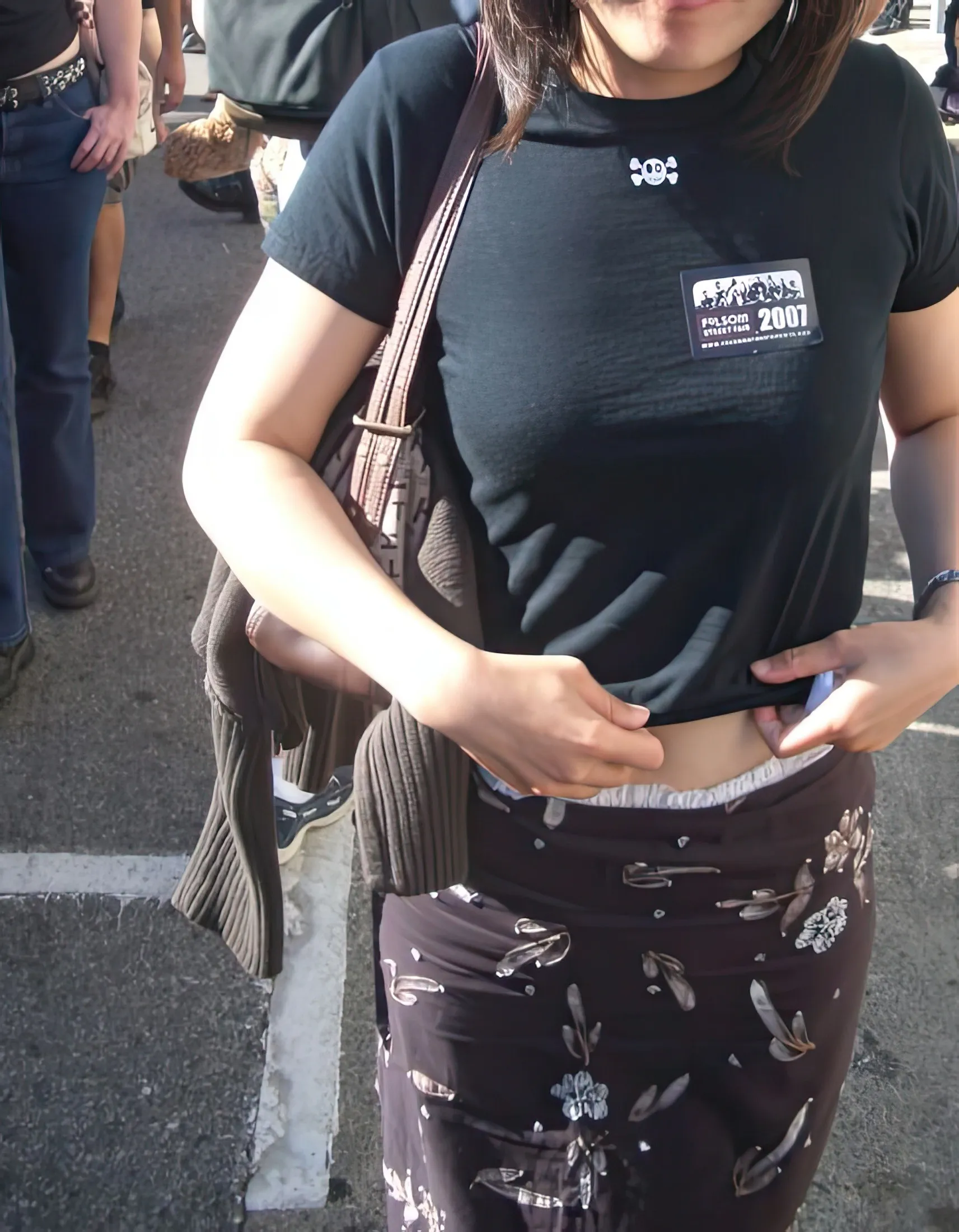An ABDL girl exposes her diaper waistband over her pants outdoors.