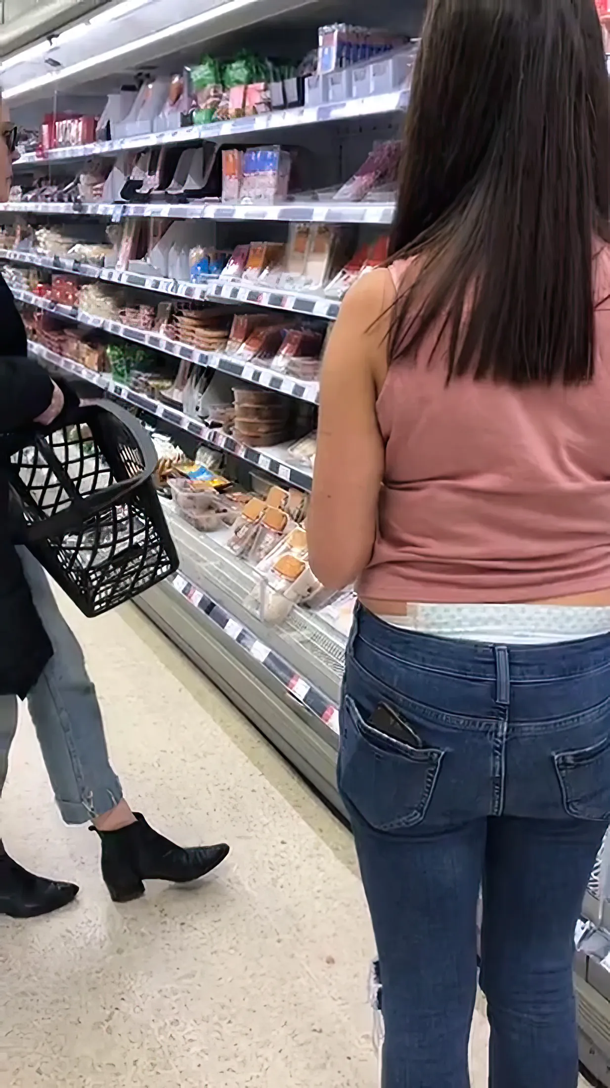 An ABDL girl exposes her diaper waistband over her jeans at the supermarket.