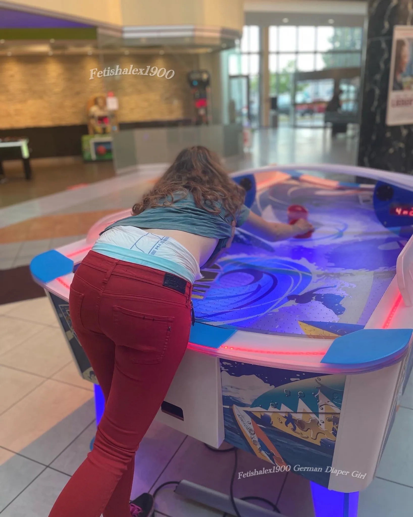 An ABDL girl is playing in the building lobby with her diaper waistband exposed.