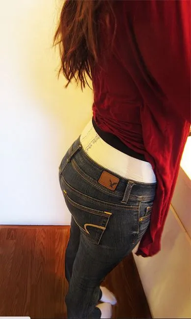 Side view of an ABDL girl with the waistband of her diaper visible over her jeans.