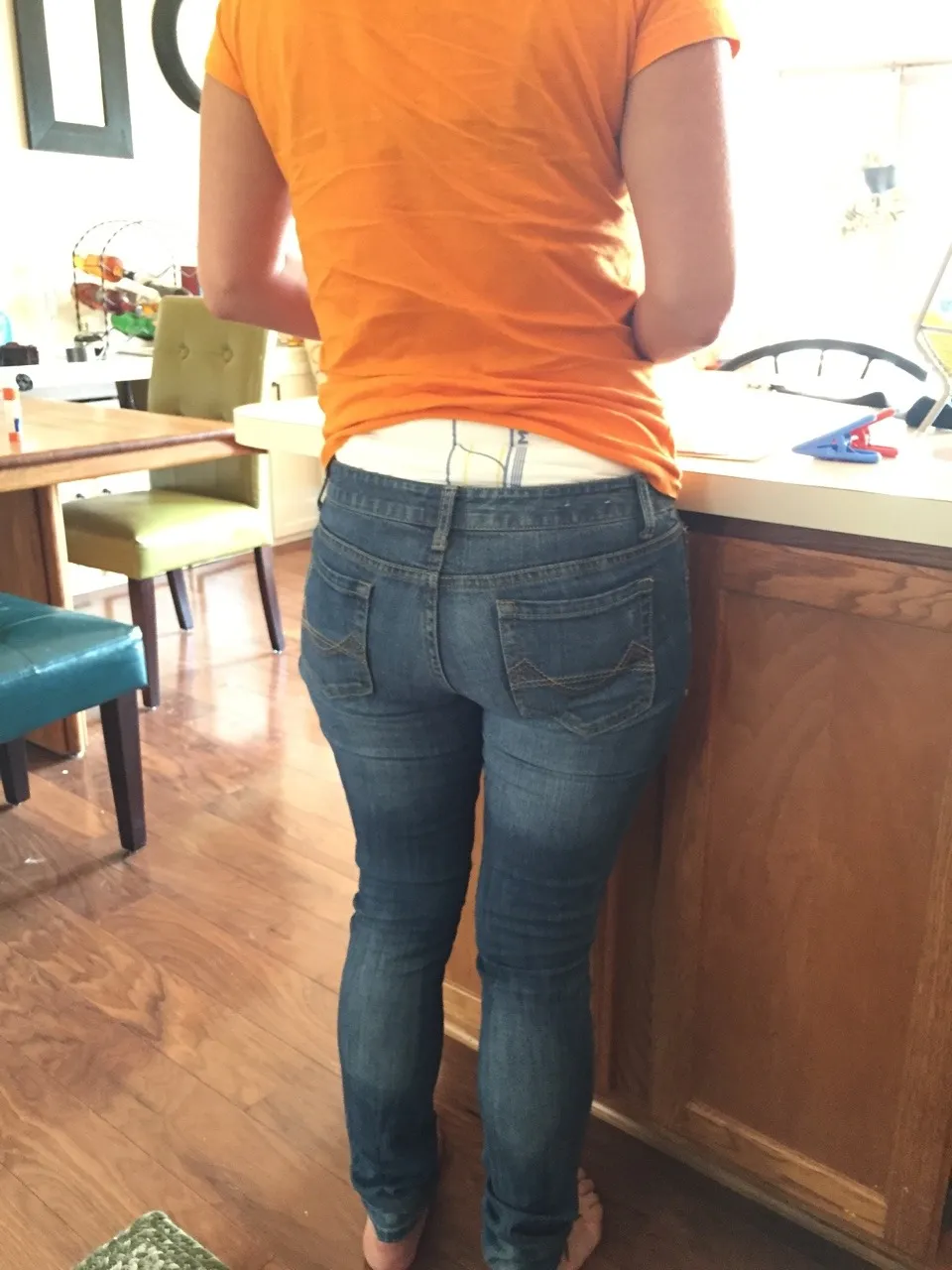 A view of an ABDL girl's backside, with the waistband of her diaper visible over her jeans.