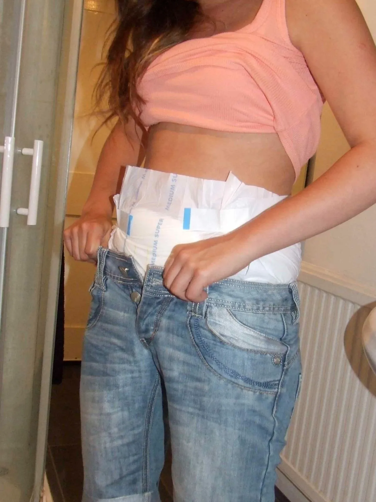 An ABDL woman flaunts her diaper waistband over her jeans.
