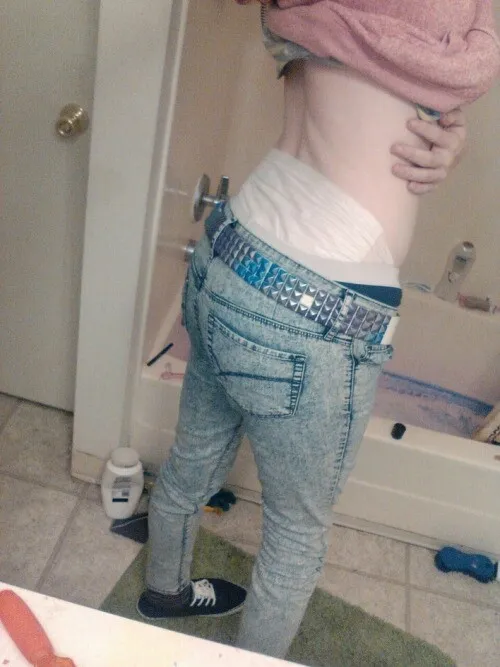 An ABDL girl shows off her diaper waistband over her jeans in the bathroom.