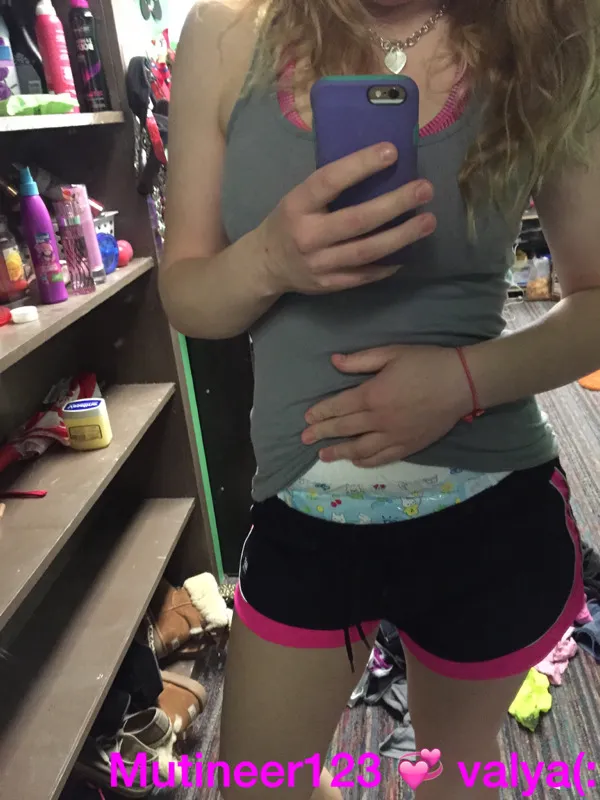 When the ABDL girl lifts her top, the diaper waistband is visible above her dolphin pants.