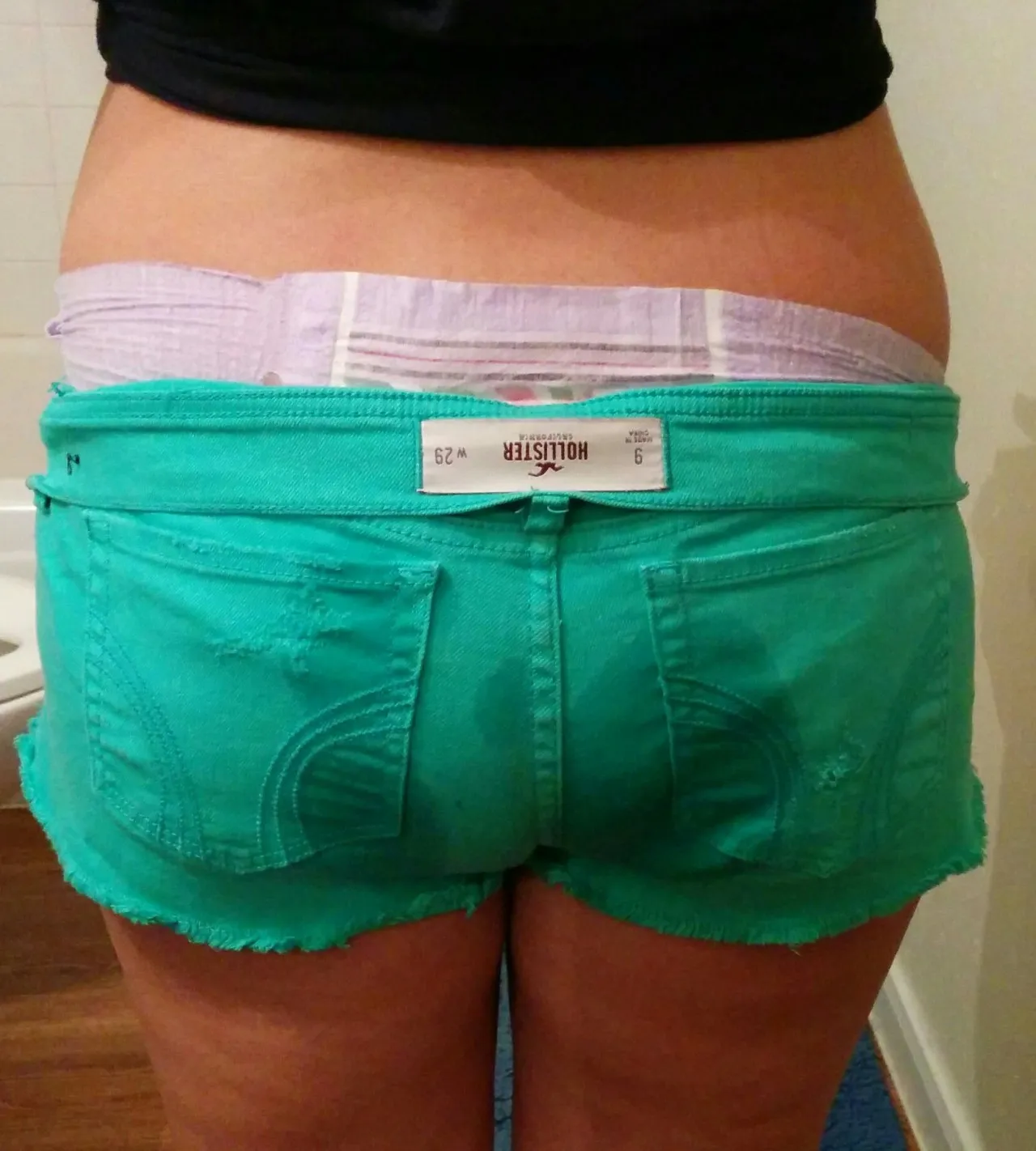 The green shorts got wet because they couldn't absorb all of the ABDL girl's pee.