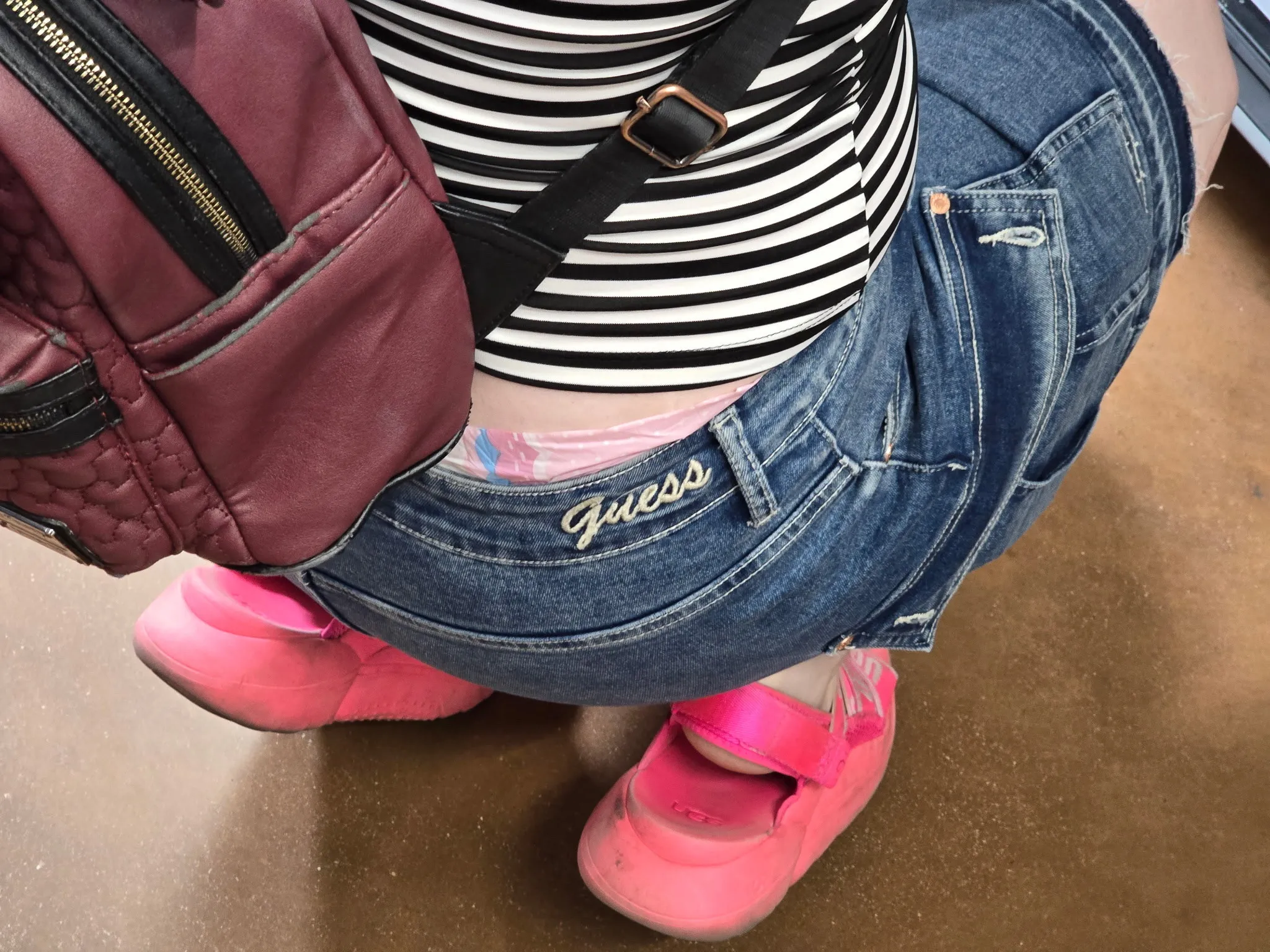 As the ABDL girl squats down, the waistband of her pull-up diaper becomes exposed.
