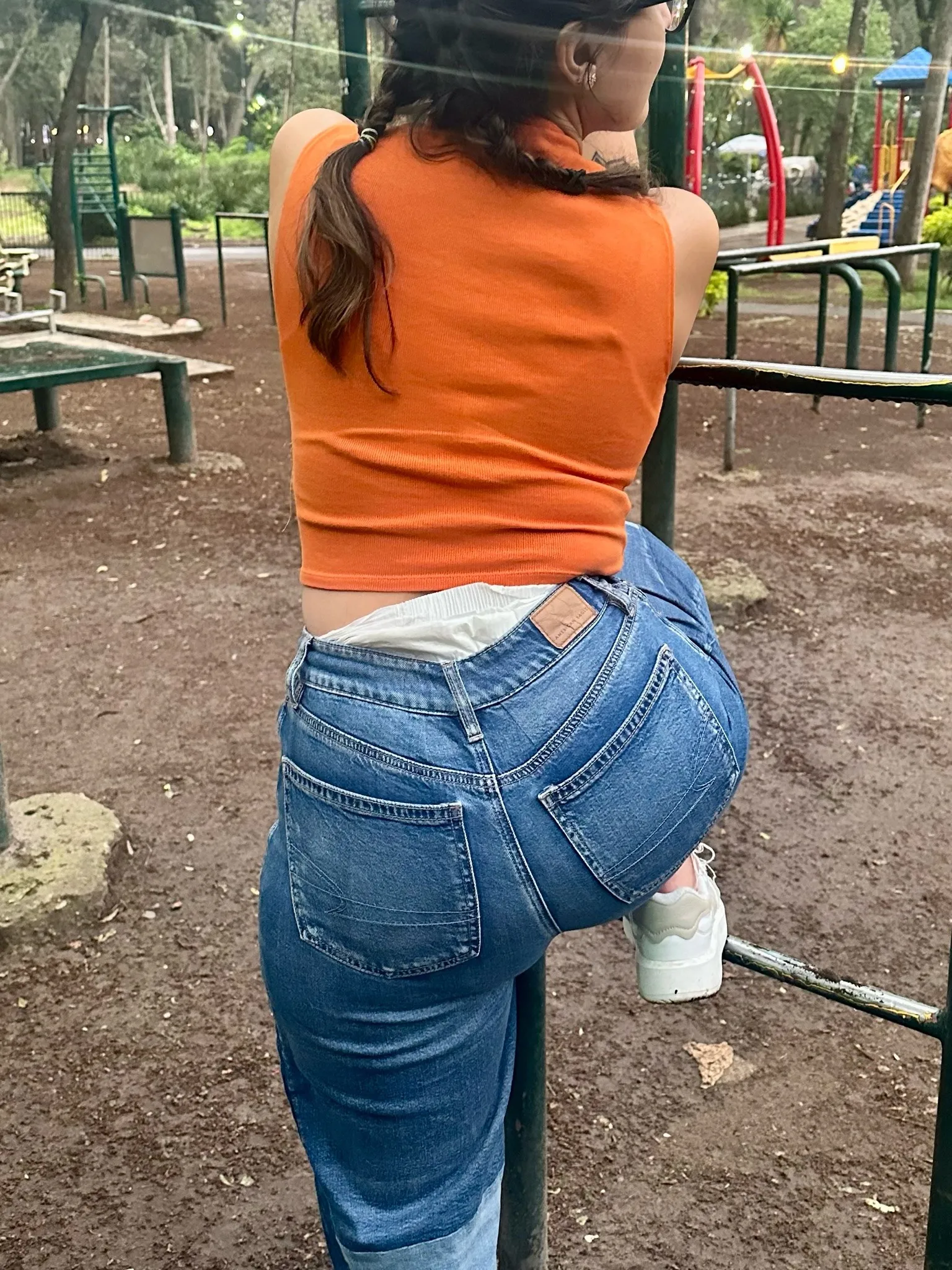 An ABDL girl bends over in a field, exposing her diaper beneath her skirt.