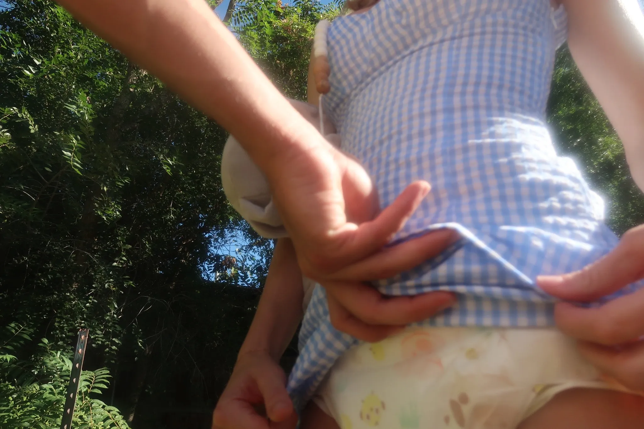 An ABDL girl's dress is pulled up by a man, exposing her diaper.