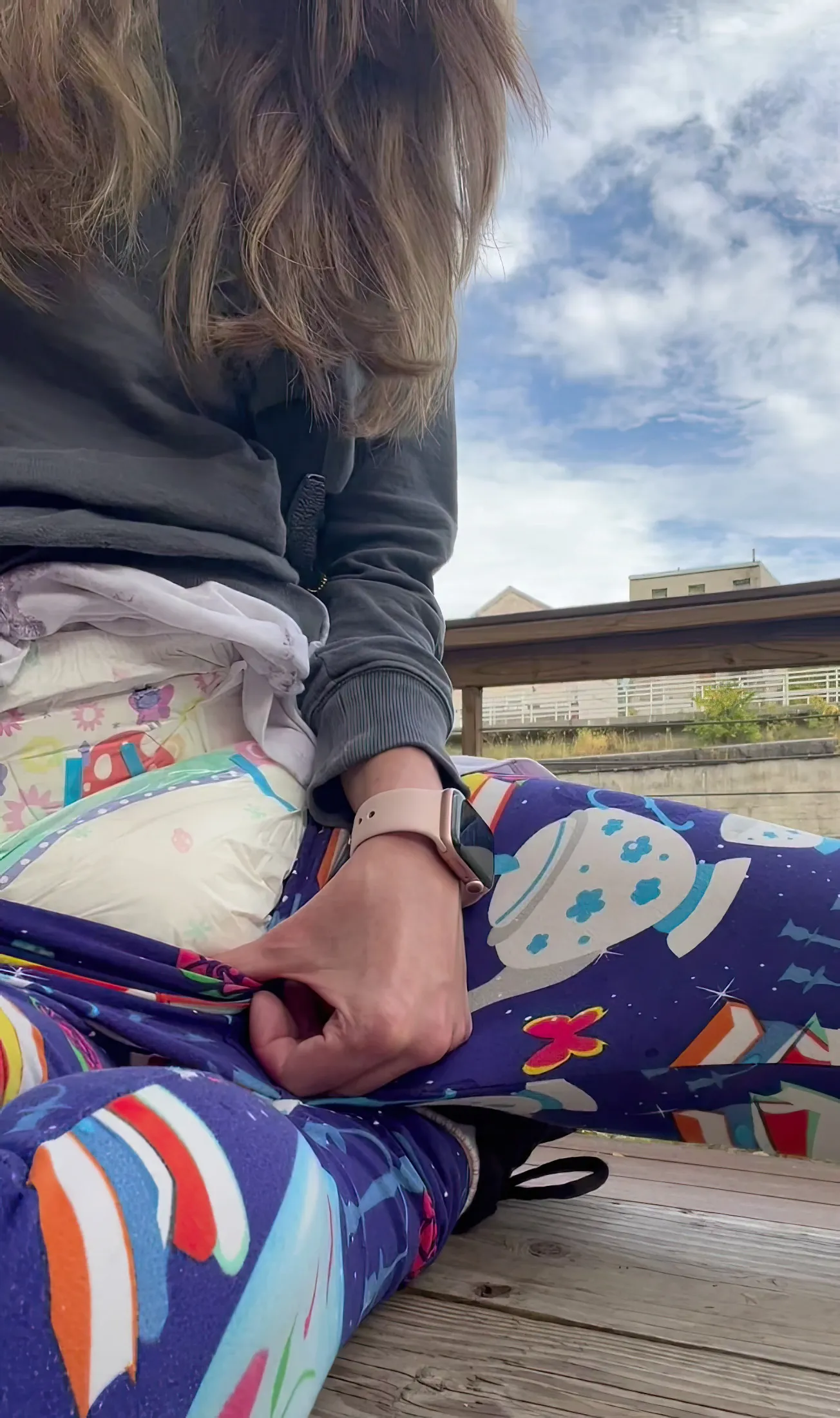 ABDL girl pulls down her leggings outdoors to show off her diaper.