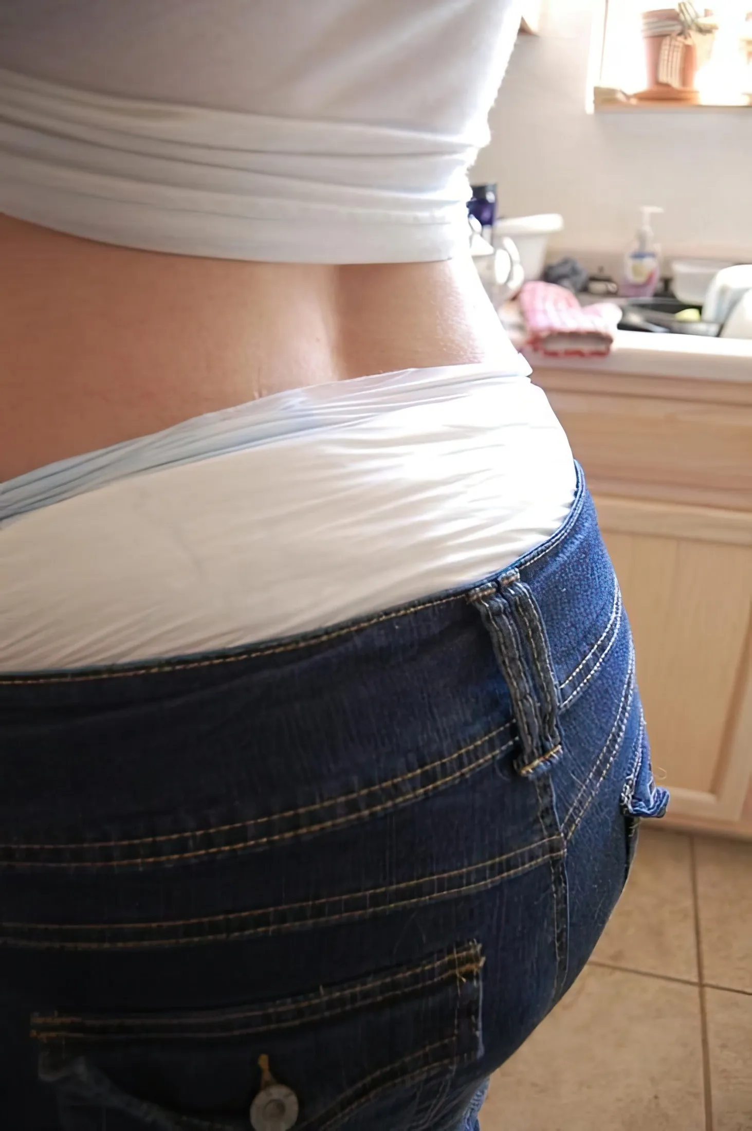 The waistband of the diaper is visible above the ABDL girl's jeans.