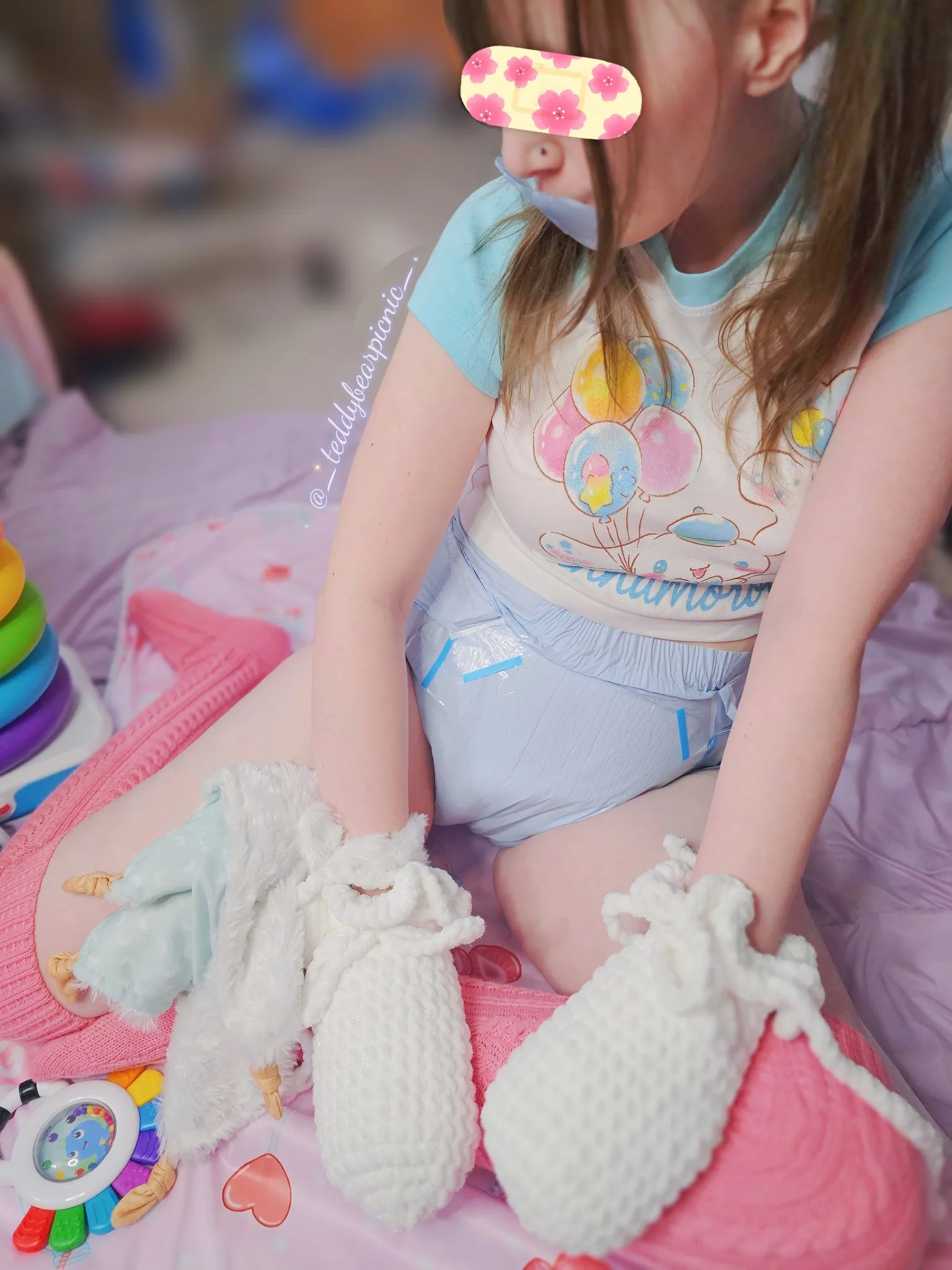 An ABDL girl wears pink knee-high socks and shows off her blue diaper.
