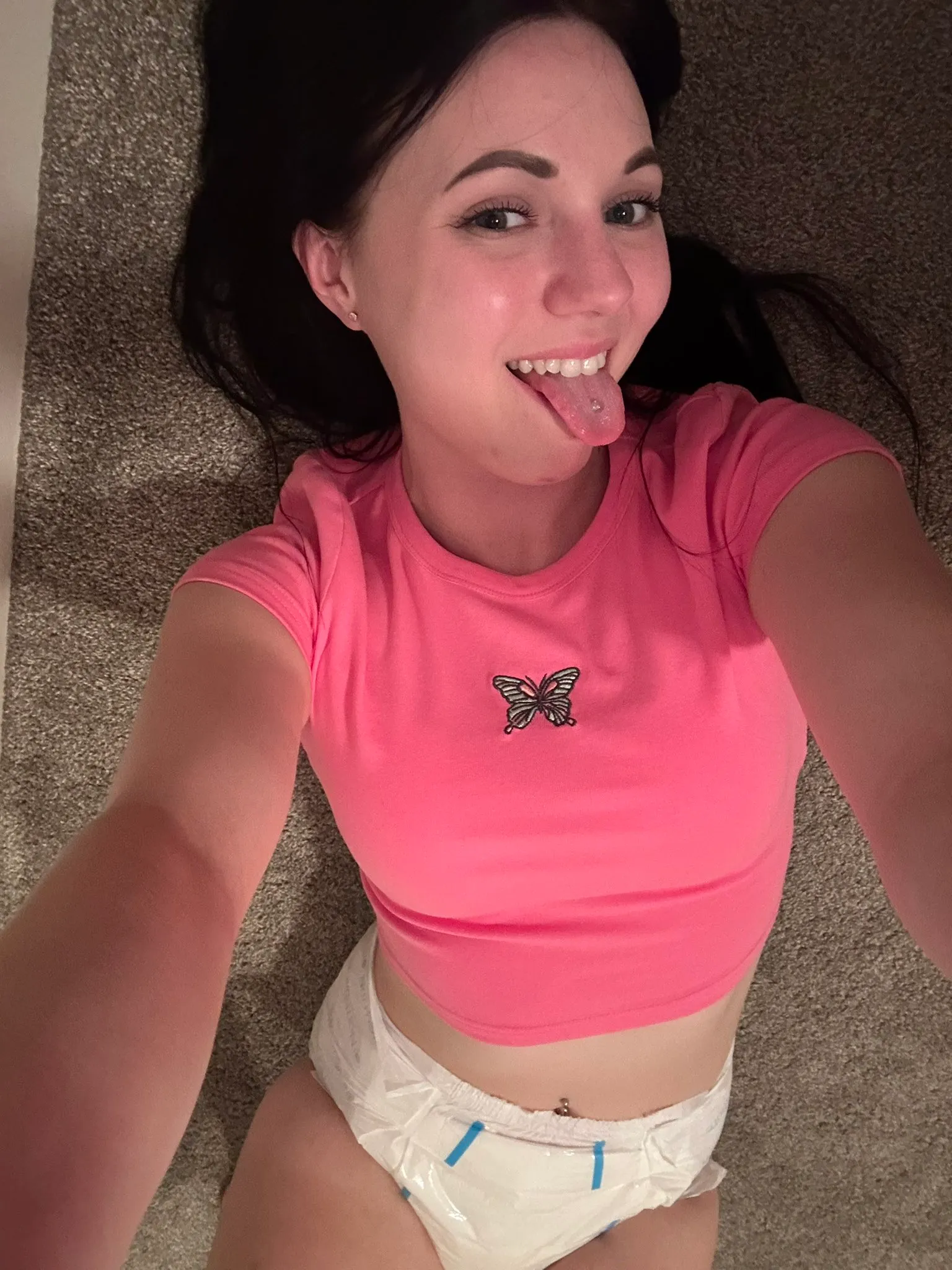 ABDL girl sticks out her tongue while exposing her diaper.