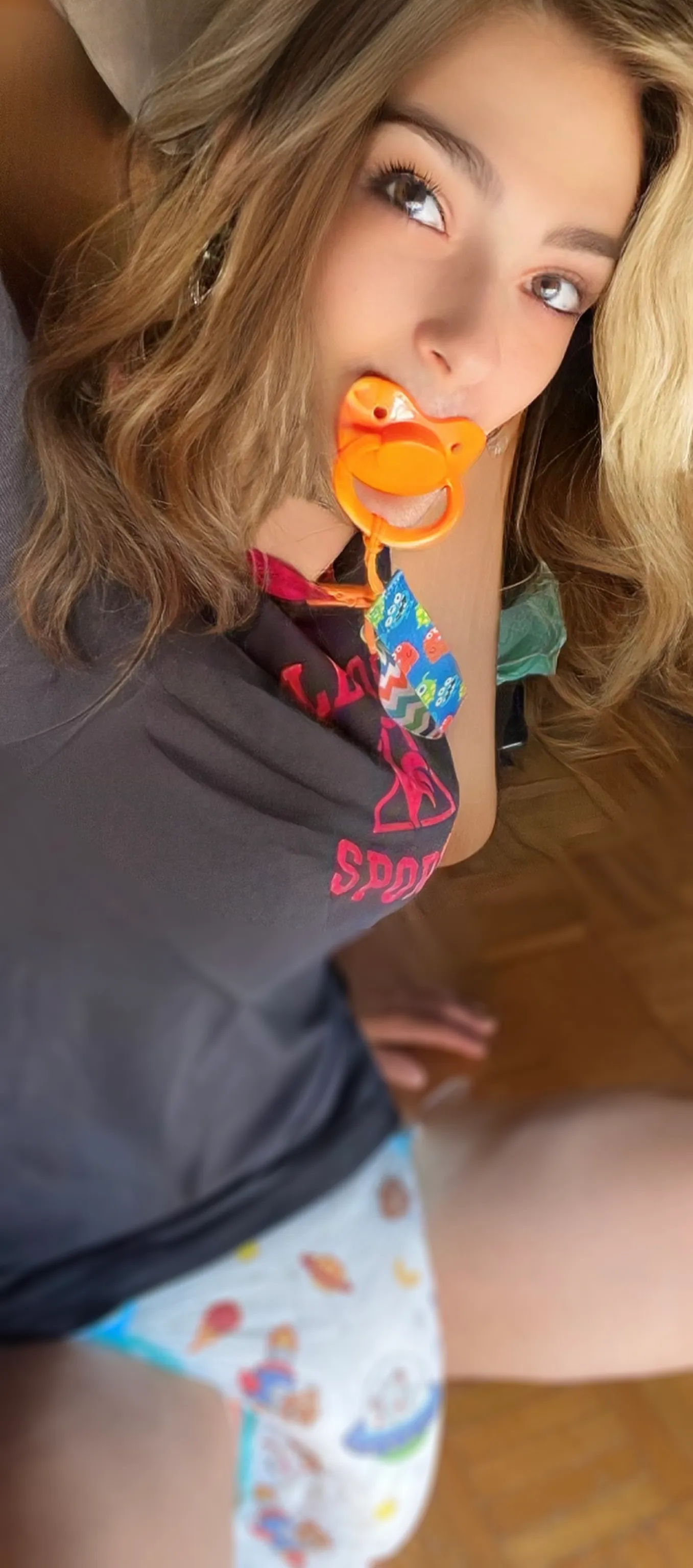 Young woman in black sporty top sucking pacifier, white printed diaper hugging her curvy hips and thick thighs